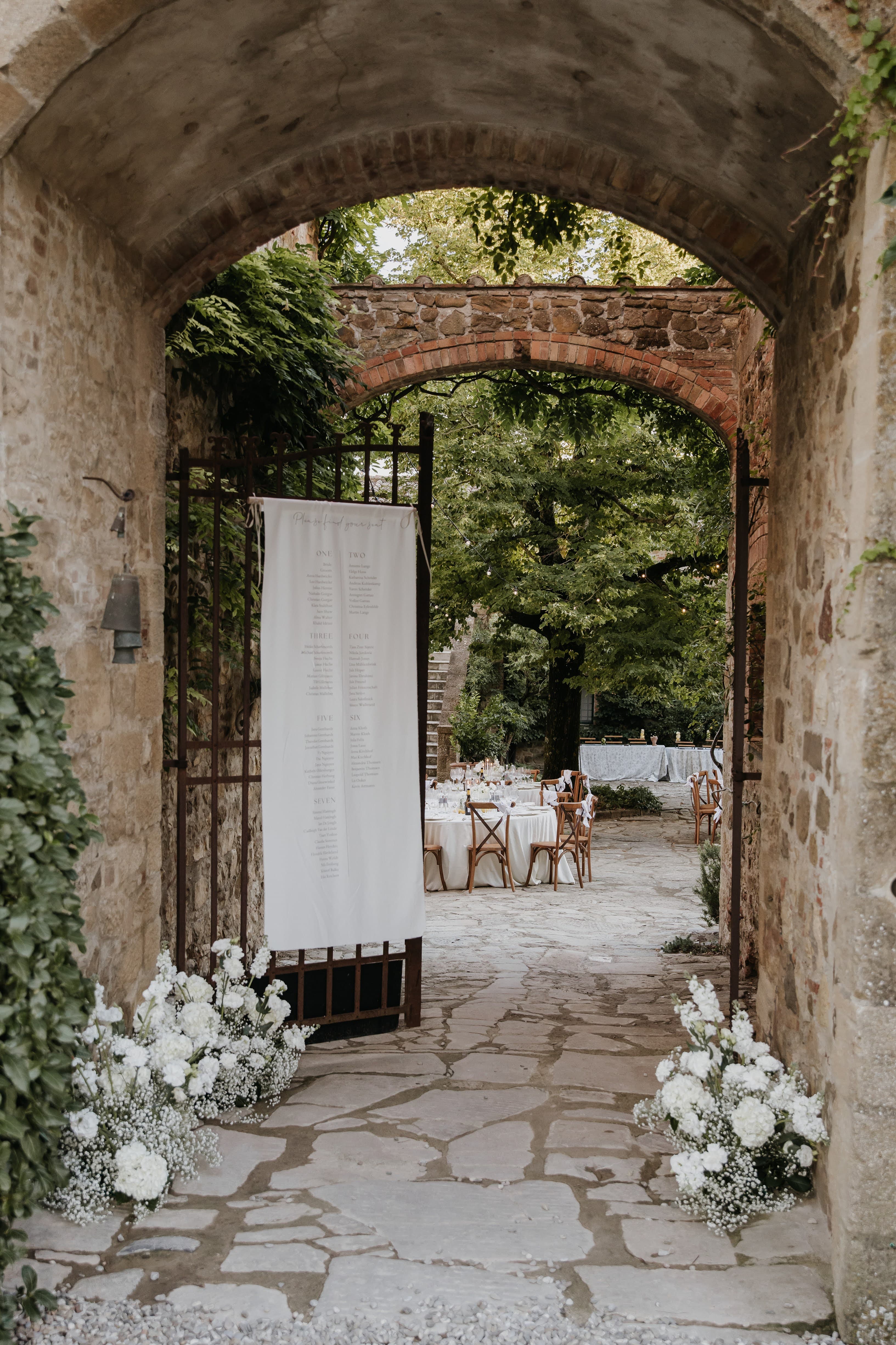 Stone archway entrance with white flowers at a Tuscan villa
